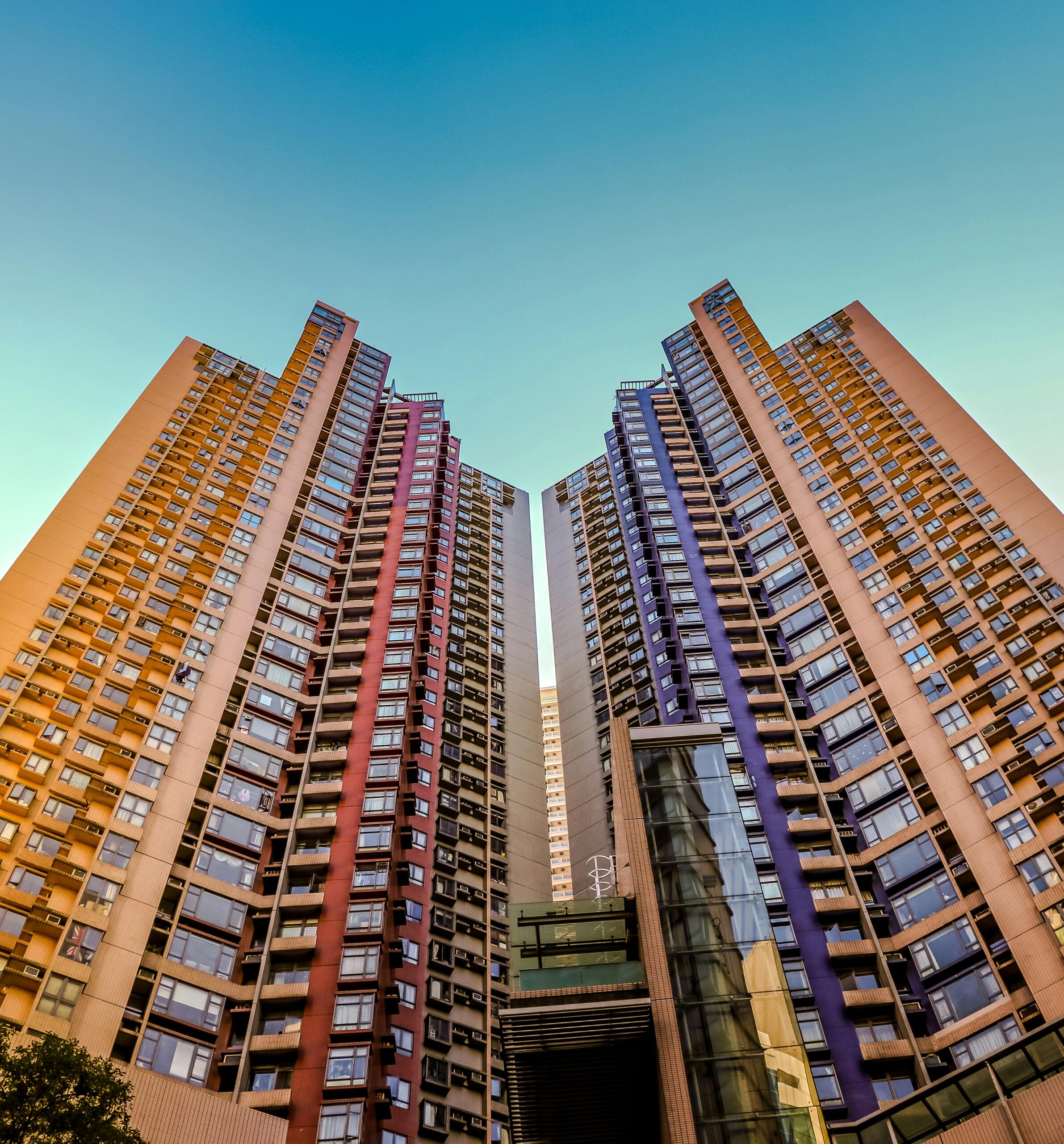 Tall, colorful skyscrapers reaching into the blue sky in Hong Kong, showcasing modern architecture.